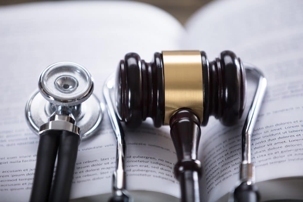 Close-up Of Stethoscope And Gavel laying atop an open book