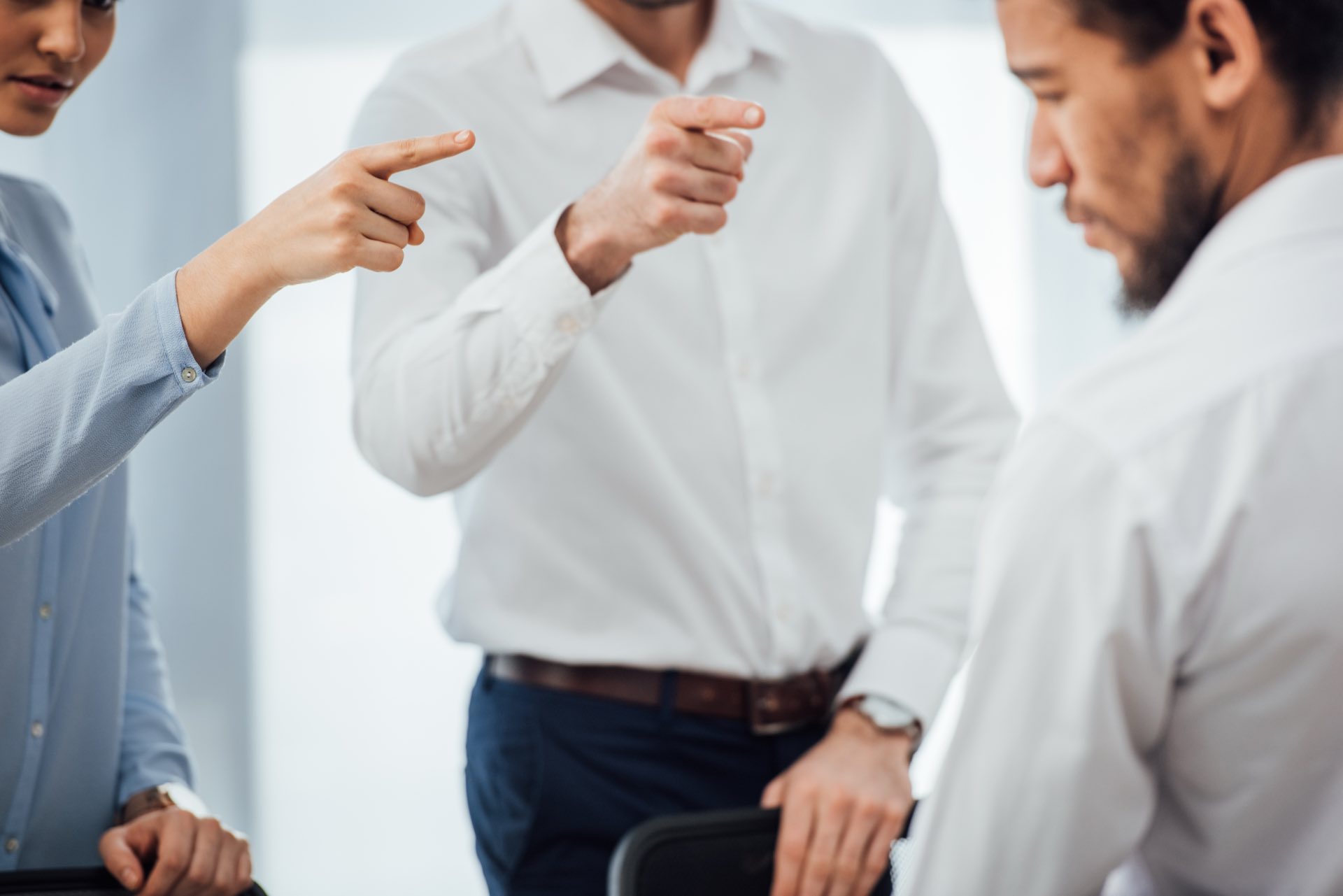 Focused on two people pointing at another individual