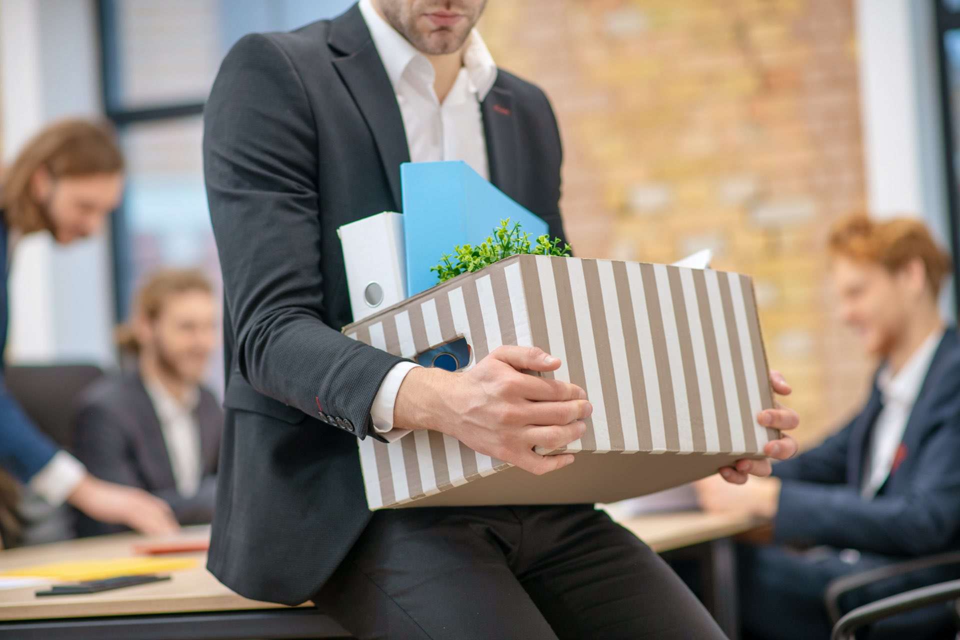 Person in suit holding a box of belongings