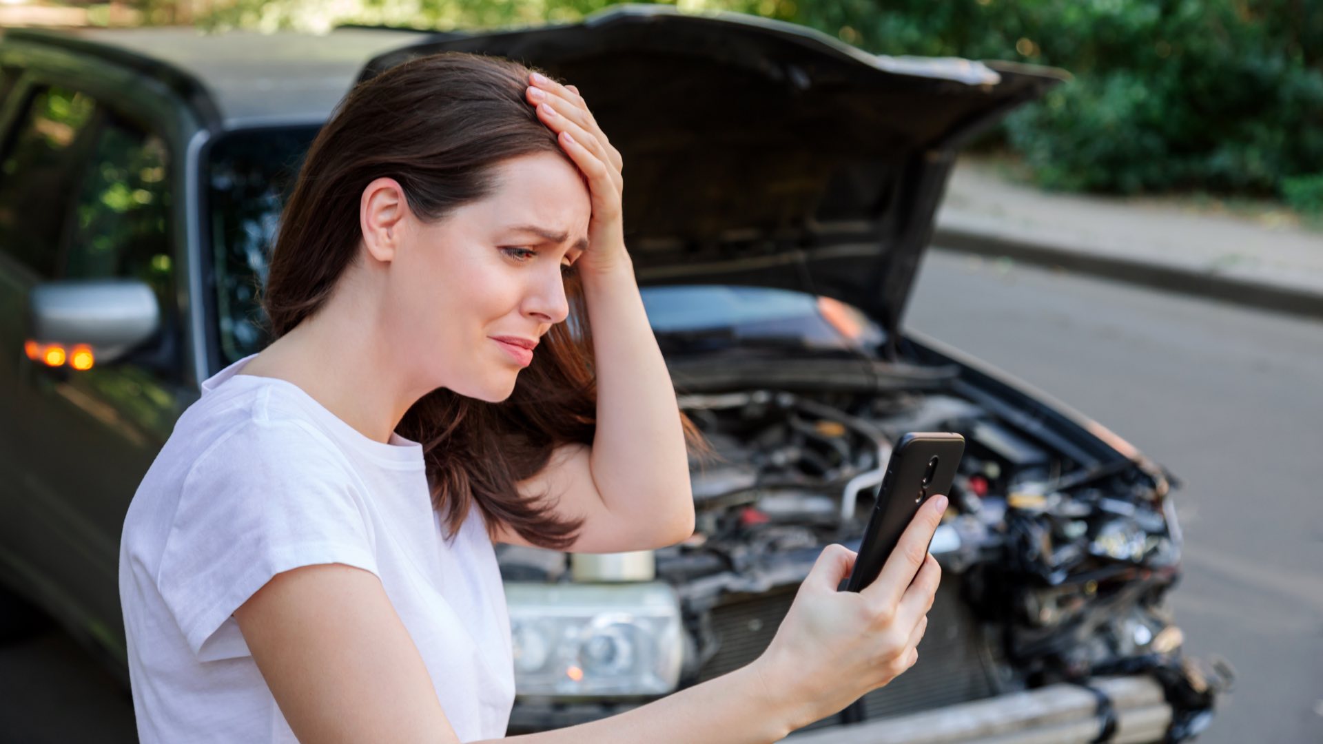 A woman holding her head and making a call after a car accident