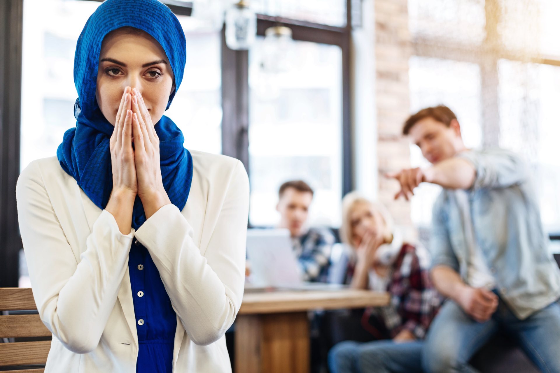 Woman with a blue scarf standing in front with people standing behind her and pointing