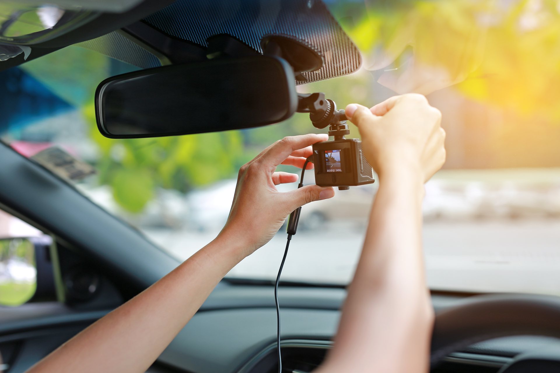 A zoomed in picture of someone's hands adjusting a dashcam