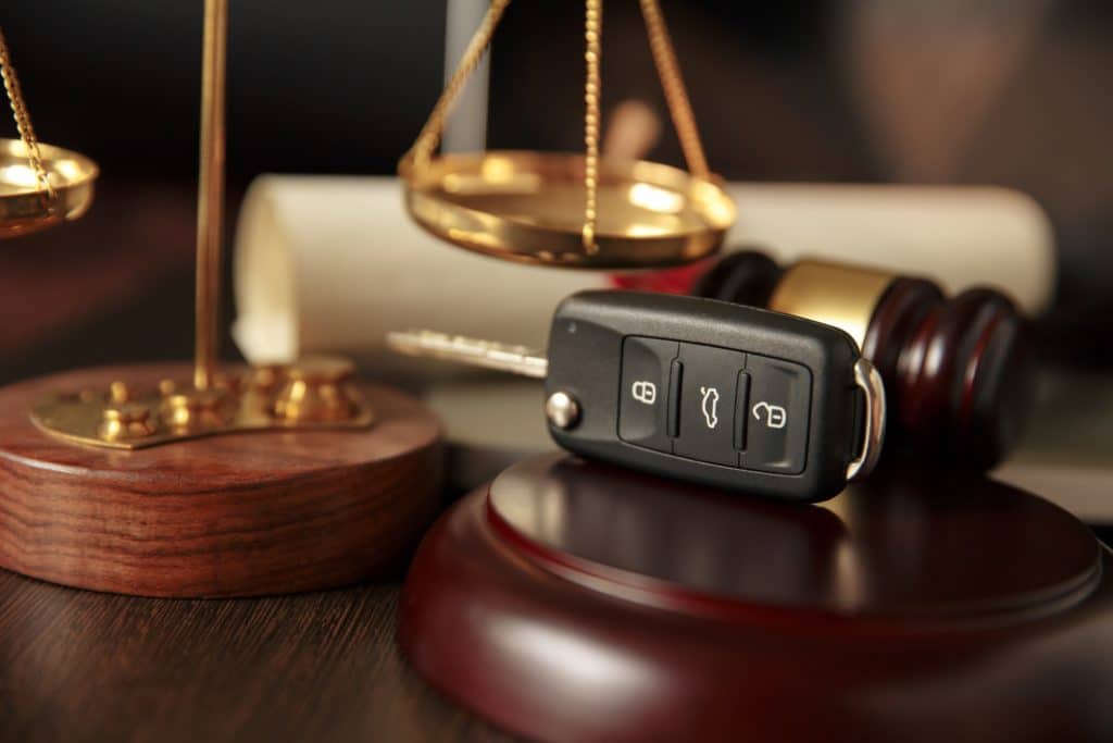 Car keys sitting atop a wooden referee, next to a gavel and the scales of justice