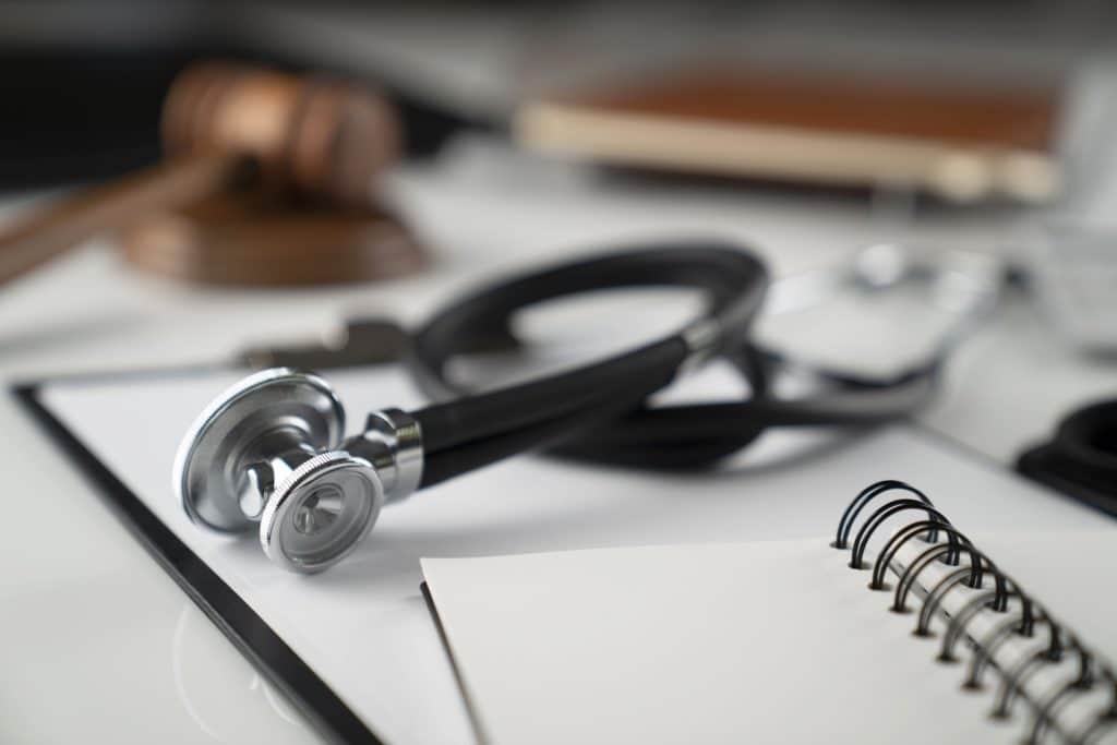 Stethoscope atop papers with blurred out gavel and block in background