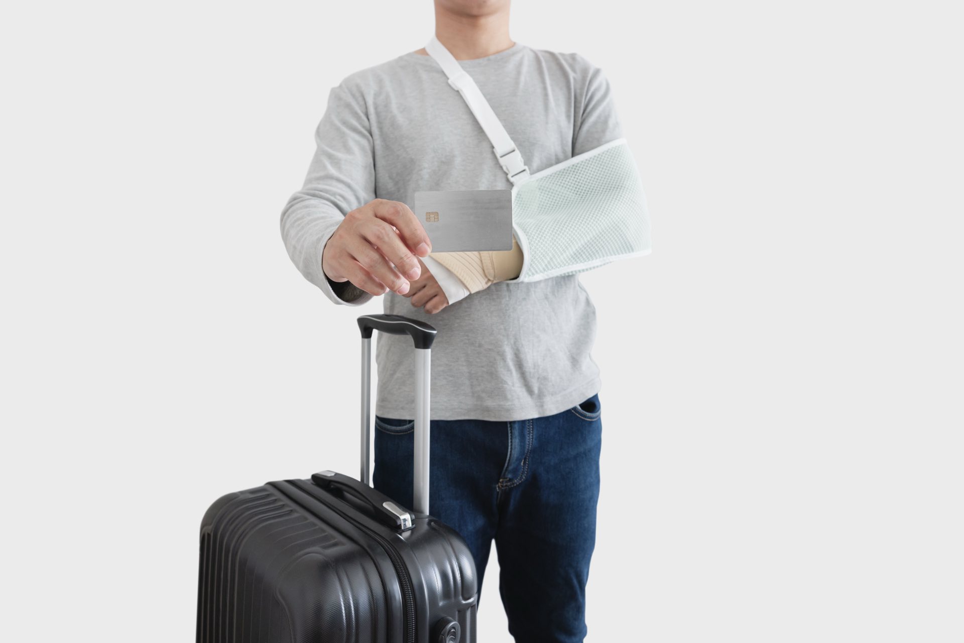 Person with a sling on arm holding a suitcase