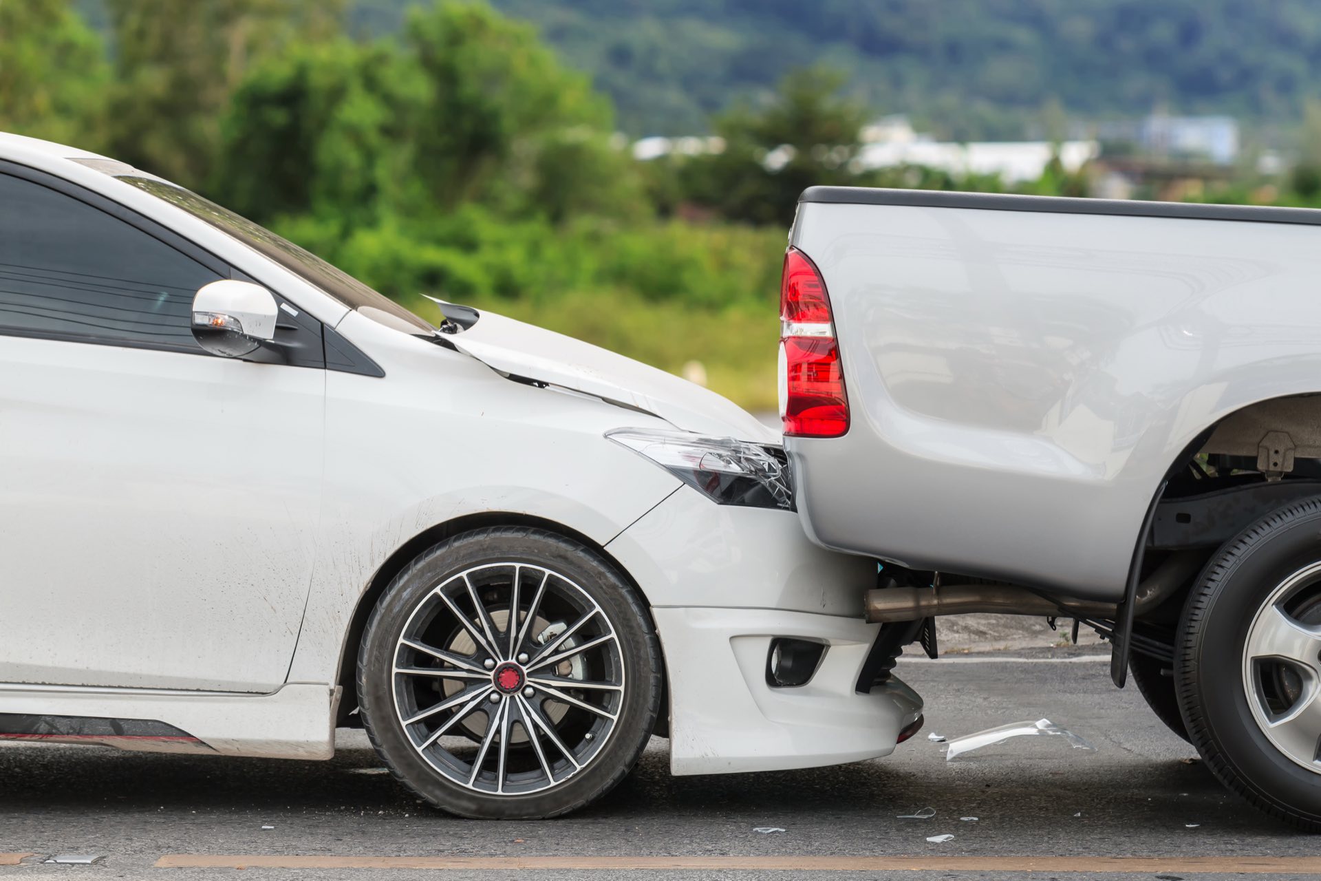 Car accident involving two cars on the road with trees in the background
