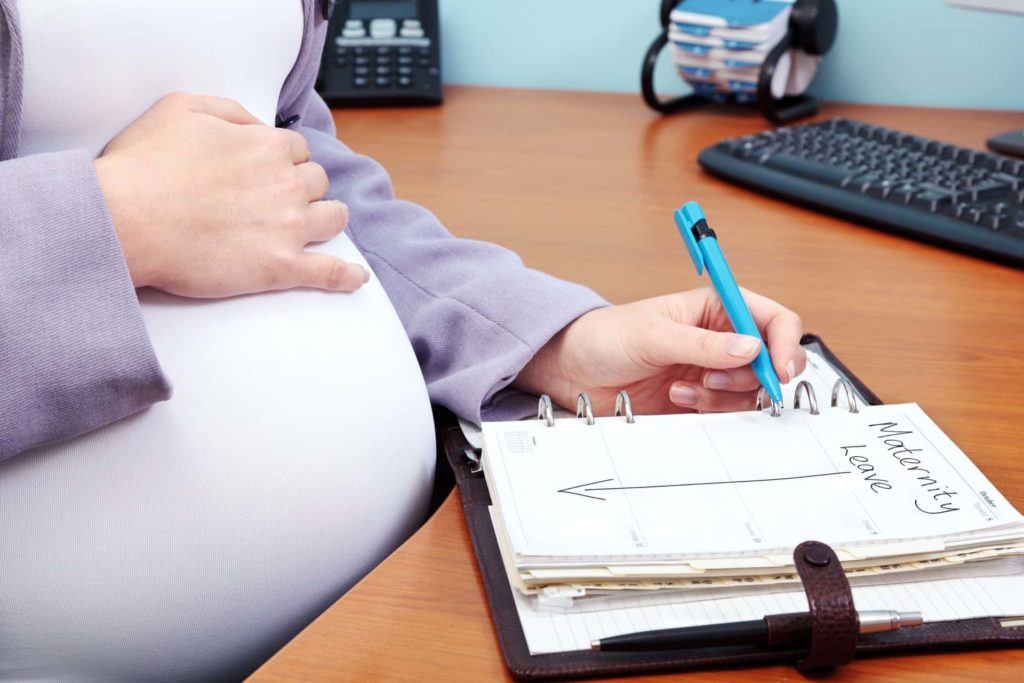 Pregnant woman marking maternity leave in calendar book