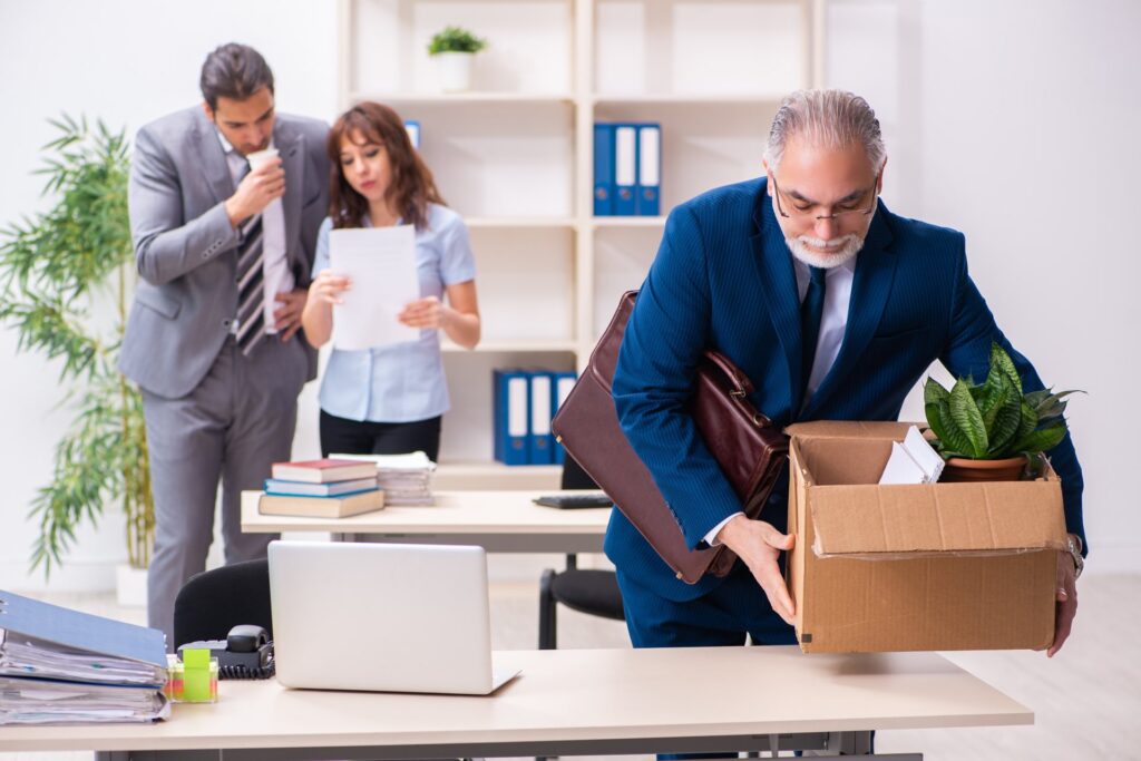 A male and female employee talking while another male employees is packing up his belongings