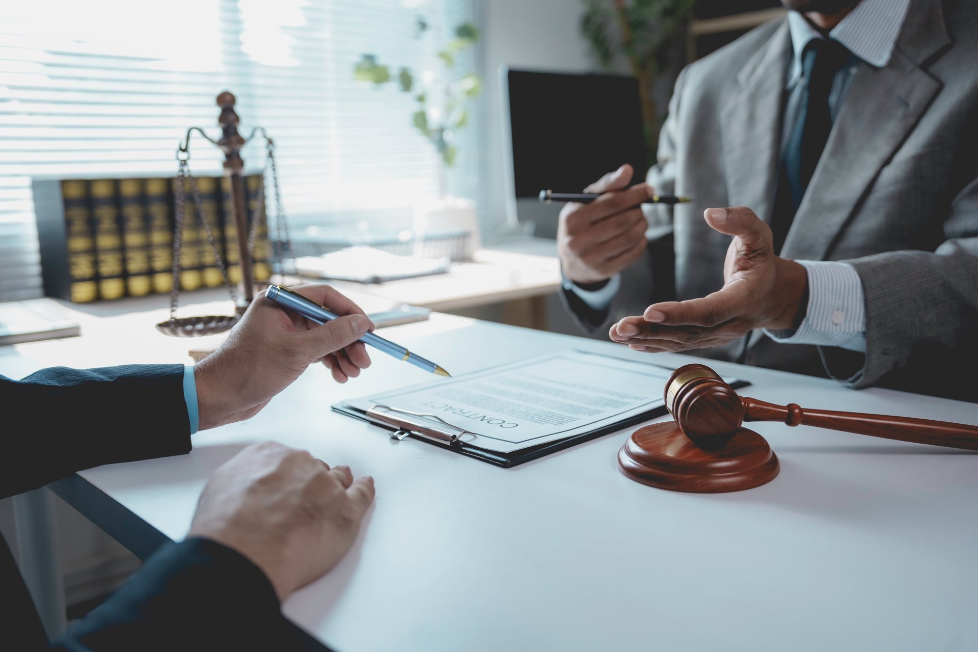 Two people discussing paperwork while holding pens