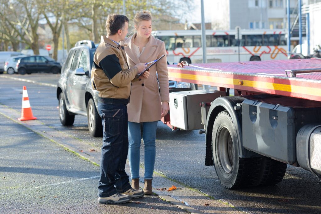 Two people standing near a truck and vehicle with one person holding a clipboard