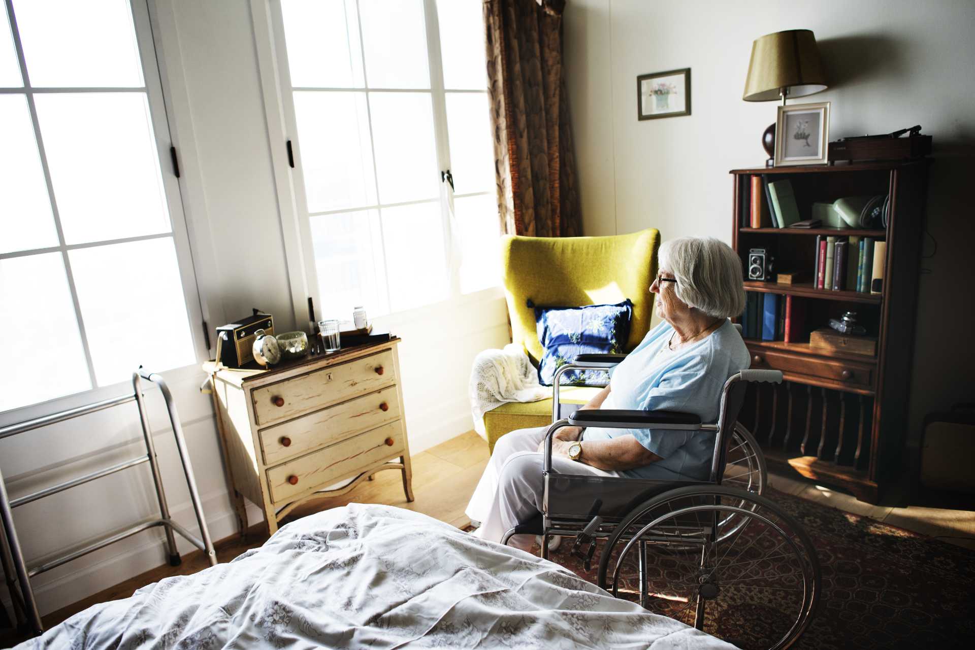 Older woman in wheelchair looking out sunlit window