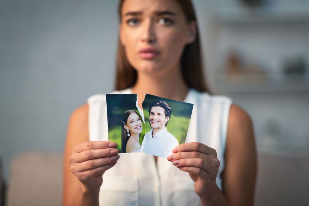 sad woman ripping photo of her and her husband