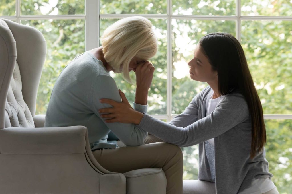 Upset older woman being consoled by daughter